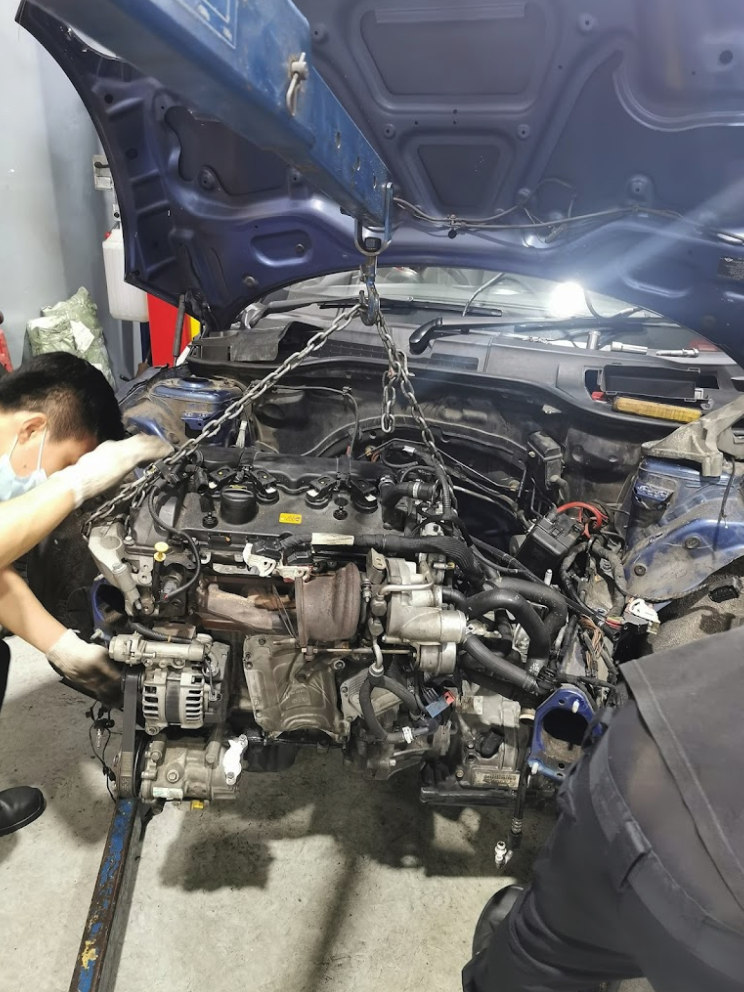 Engine being lifted out of a car at the best engine overhaul workshop in Singapore