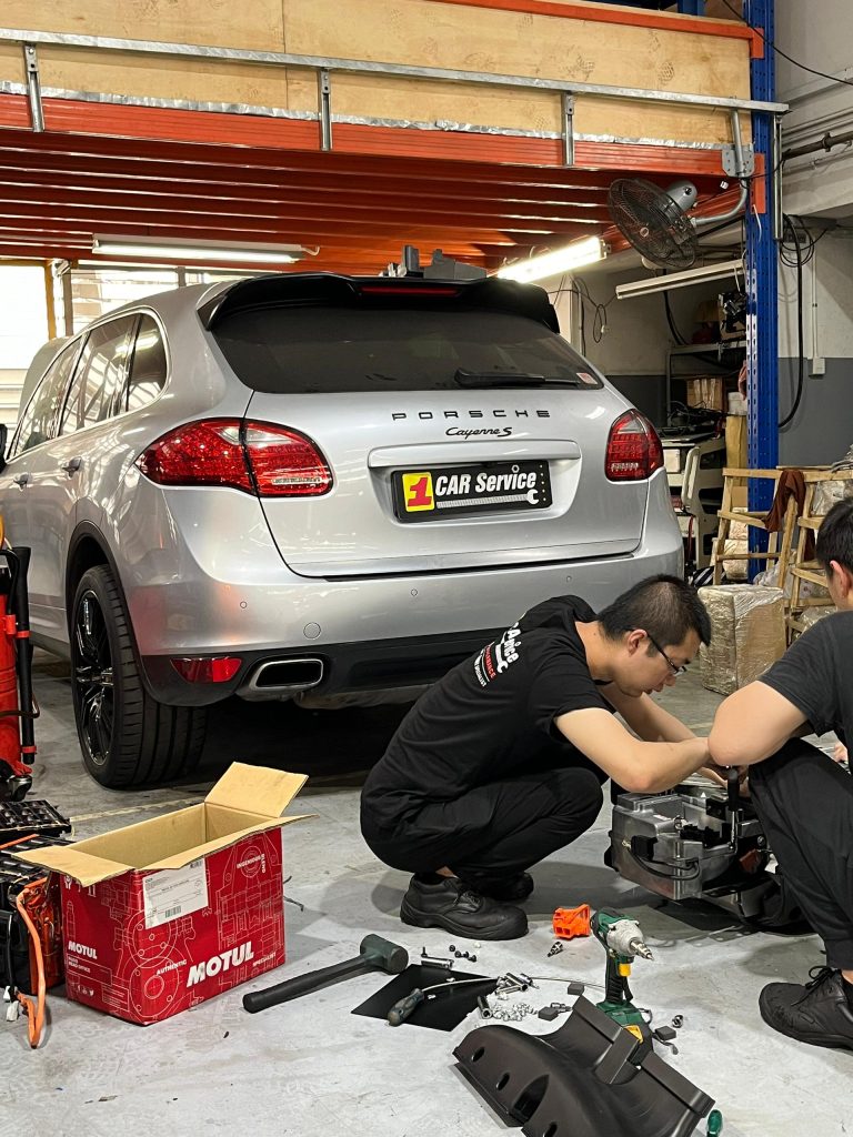 Technicians at 1 Car Service Workshop repairing a hybrid battery in a Porsche.