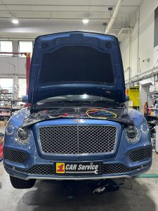 A mechanic diagnosing a car's air conditioning system with professional tools in a workshop.
