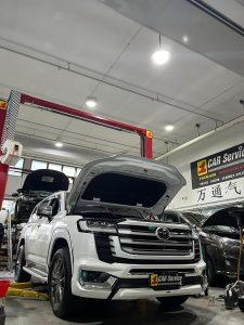 A mechanic using diagnostic tools to inspect the car aircon system in a workshop.