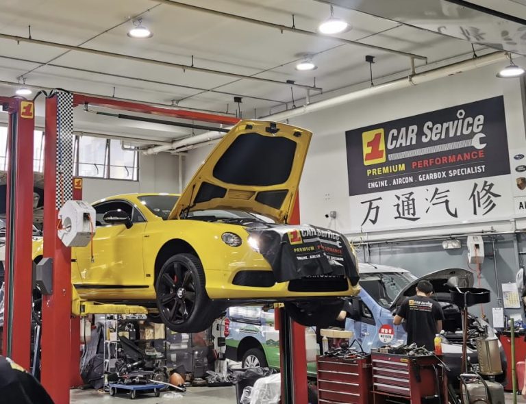 Mechanics performing a detailed repair on a Bentley in a professional car service workshop.